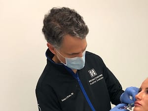 Dr. Bruno injecting lip filler on a young patient